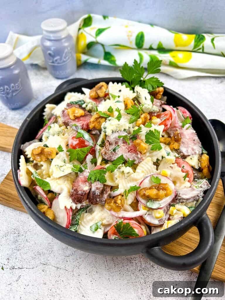 Steak and pasta salad in a black bowl.