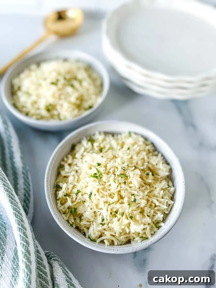 Two white bowls of Instant Pot Rice with a stack of white plates, striped cloth, and golden serving spoon at the background.