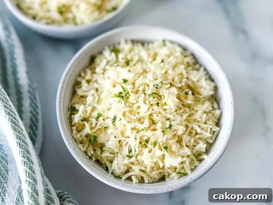 Two white bowls of Instant Pot Basmati Rice with a stack of white plates and golden serving spoon at the background.