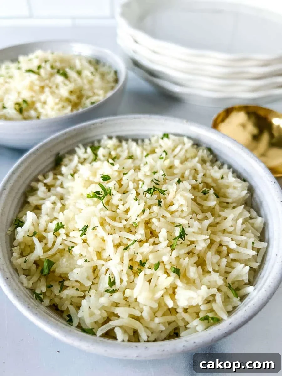 Two white bowls of Instant Pot Basmati Rice with a stack of white plates and golden serving spoon at the background.