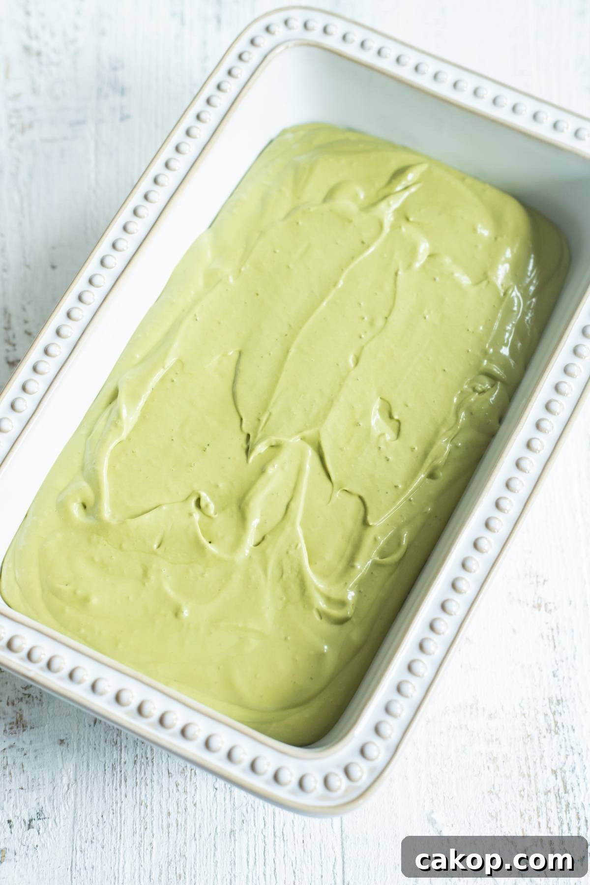 No-Churn Matcha Dulce de Leche Ice Cream Recipe 17 A white rectangular dish filled with smooth, light green matcha ice cream, made without a machine, sits on a white surface.