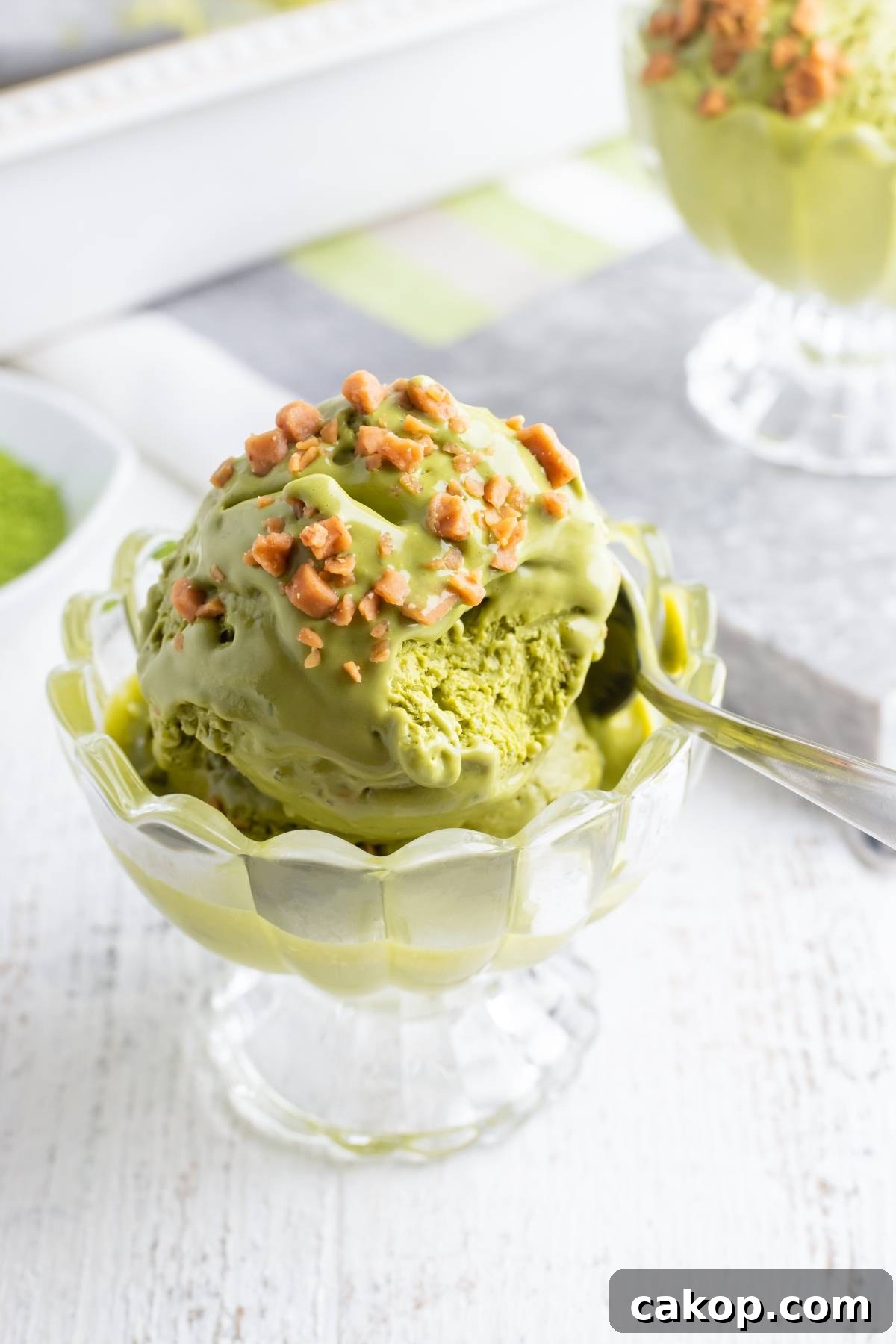 No-Churn Matcha Dulce de Leche Ice Cream Recipe 3 A glass dish of matcha green tea ice cream topped with chopped nuts and a spoon—try this no churn ice cream recipe for a creamy treat without an ice cream machine.