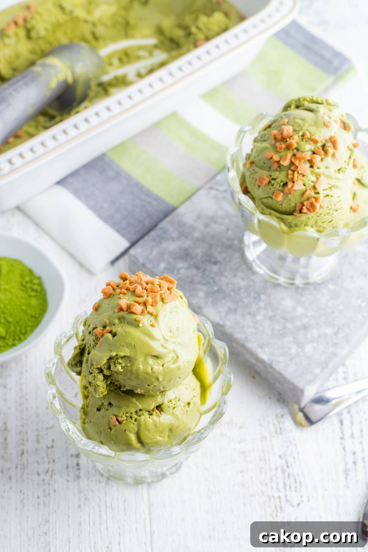 No-Churn Matcha Dulce de Leche Ice Cream Recipe 7 Two glass bowls of green No Churn Matcha Dulce de Leche Ice Cream topped with crunchy nuts sit on a white table—the perfect matcha ice cream recipe without a machine for homemade dessert lovers.