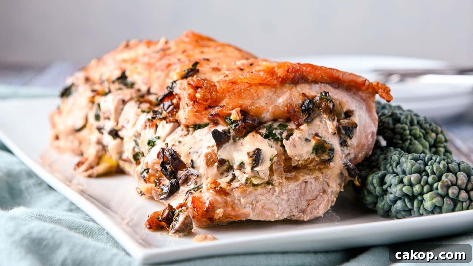 A rectangle platter with a stuffed pork on it with kale on the side