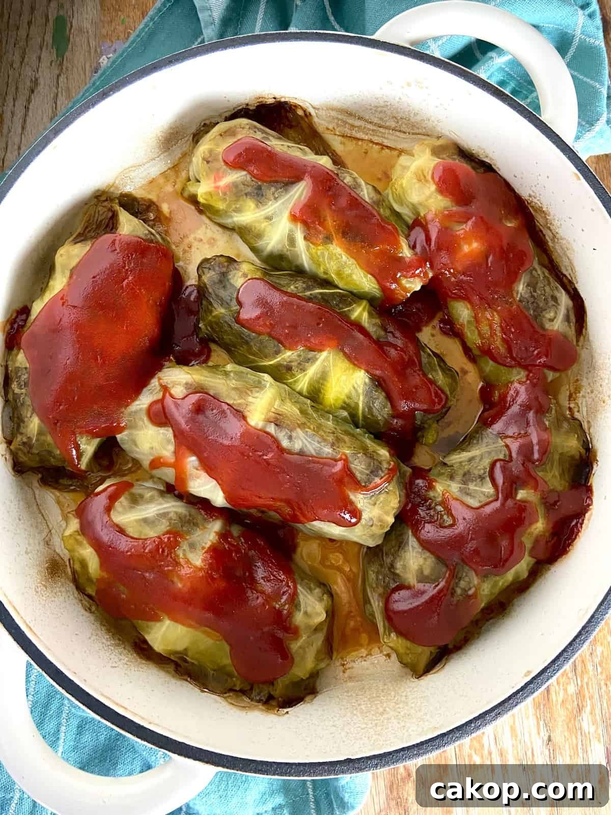 Cabbage rolls in Dutch oven topped with tomato sauce.