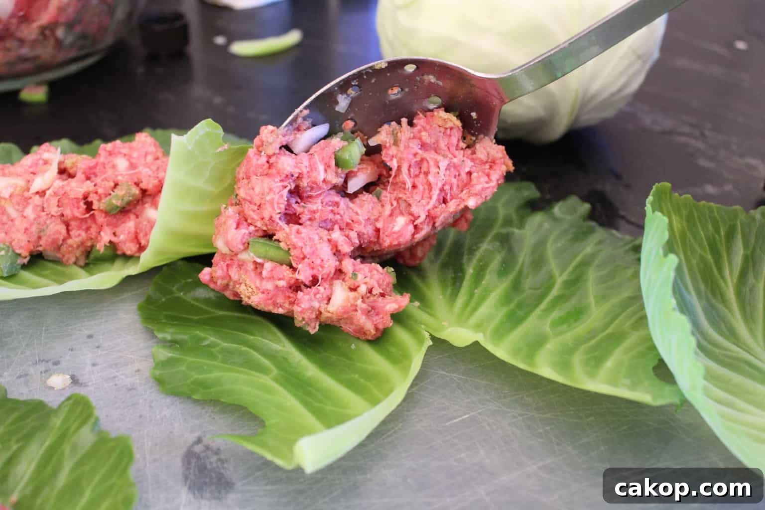 Meat mixture being spooned onto leaf.