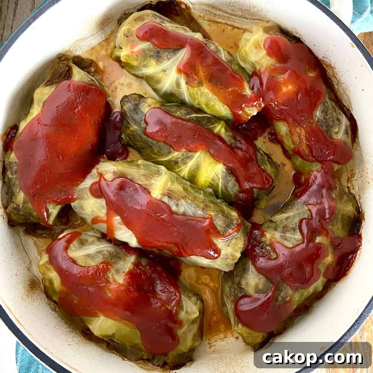 Cabbage rolls in Dutch oven topped with tomato sauce.