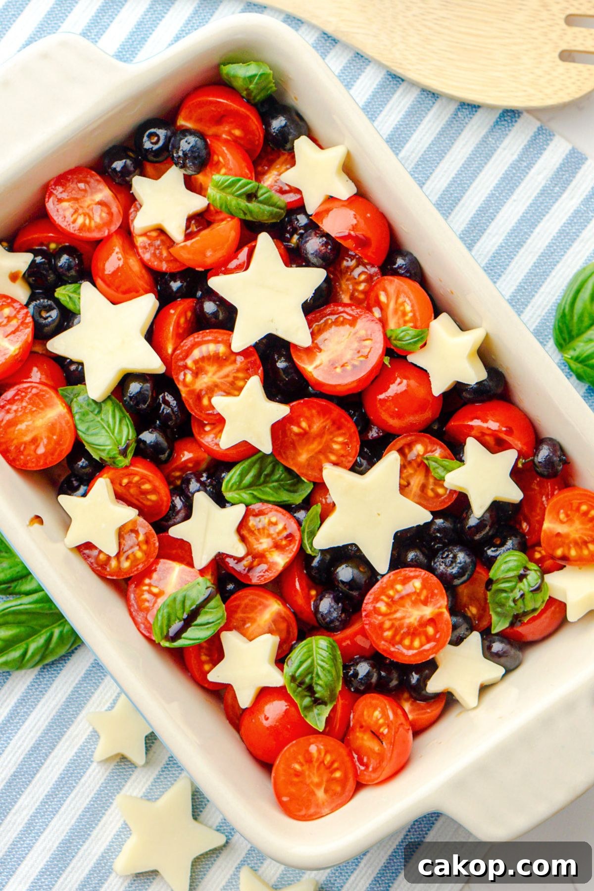 Berry Caprese Salad with Fresh Mozzarella and Balsamic 2 Blueberries, tomatoes, and mozzarella cheese shaped into stars, in a rectangle baking dish.