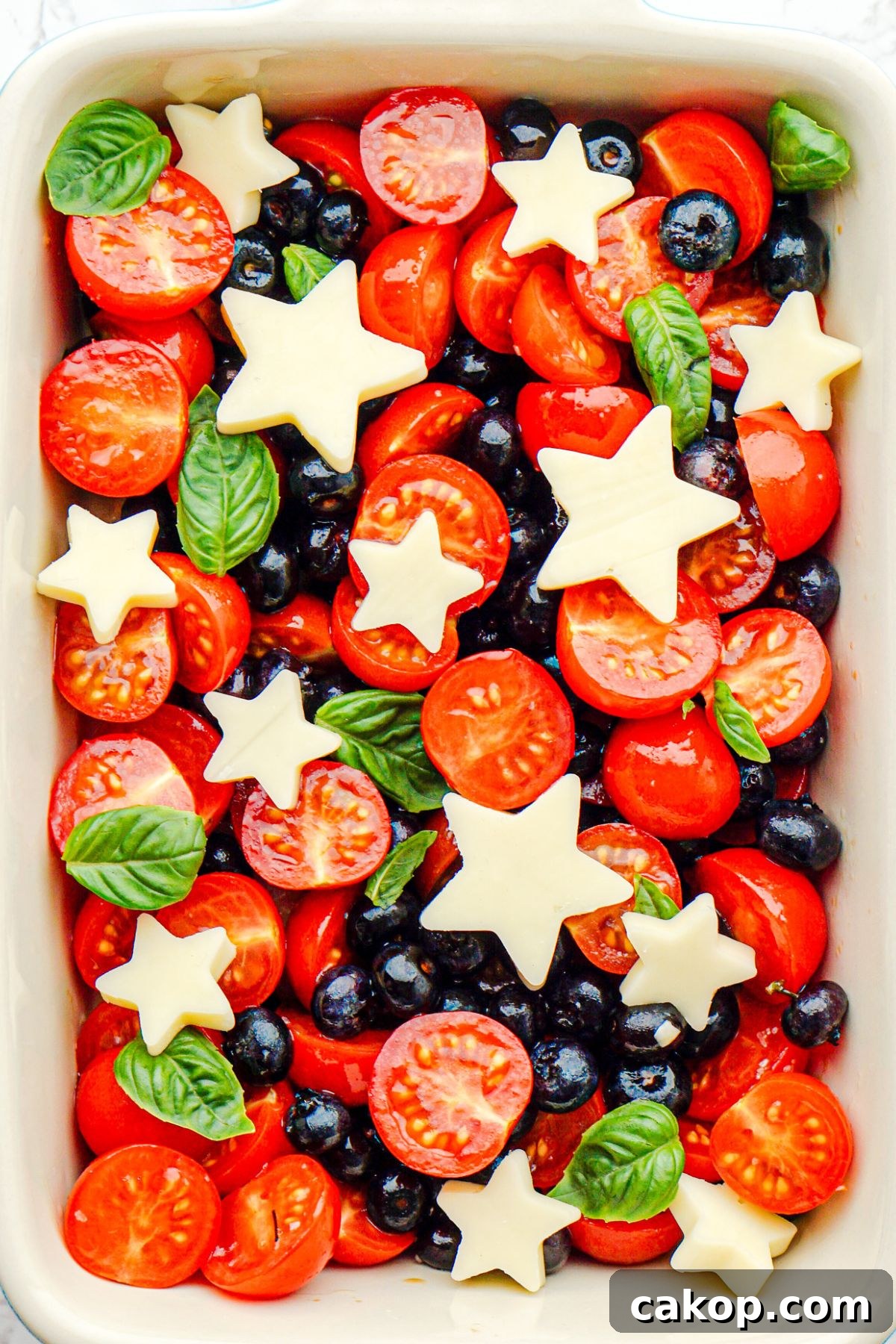 Berry Caprese Salad with Fresh Mozzarella and Balsamic 7 Blueberries, tomatoes, and mozzarella cheese shaped into stars, in a rectangle baking dish.