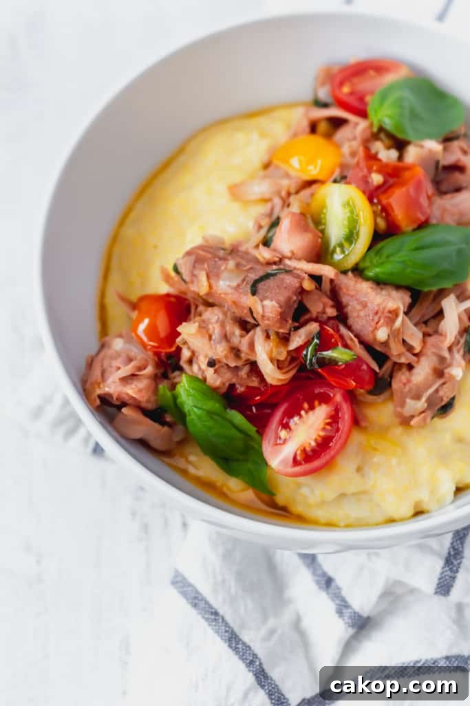 This vegan grits recipe is the perfect gluten-free meal! Creamy vegan polenta cooked in coconut milk is topped with savory jackfruit confit with tomatoes and basil!