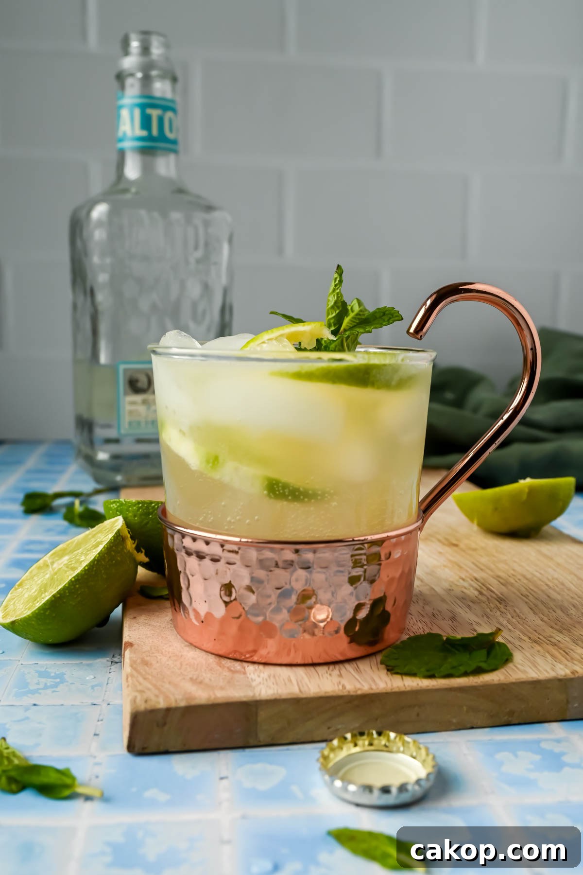a copper mug filled with tequila mule, lime wedges, and mint sprigs.