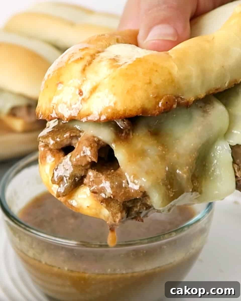 Bite shot of Easy French Dip Sandwiches dipped in au jus