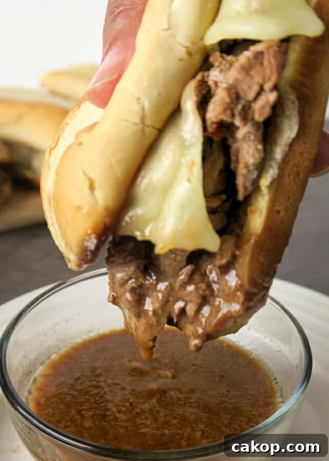 Easy French Dip Sandwiches being dipped into au jus gravy sauce