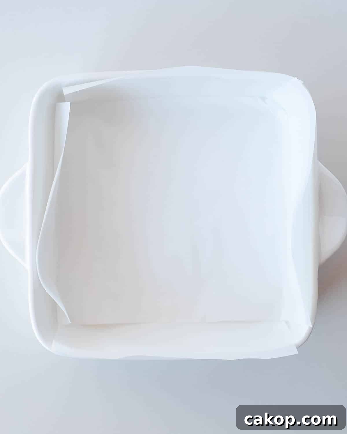 8x8 baking dish lined with parchment paper prepared for 3 ingredient banana brownies.