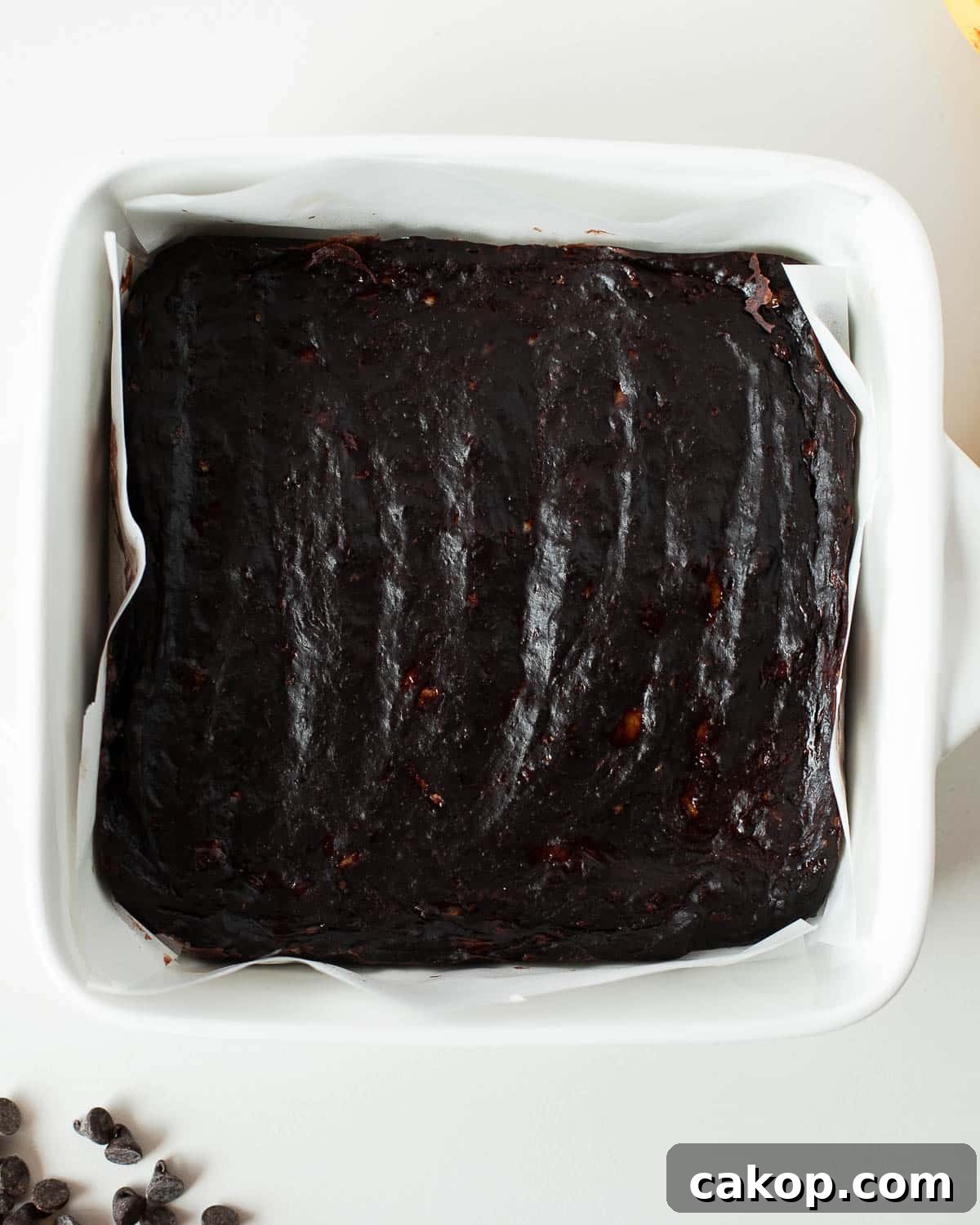 Freshly baked 3 ingredient banana brownies in a square baking pan lined with parchment paper.