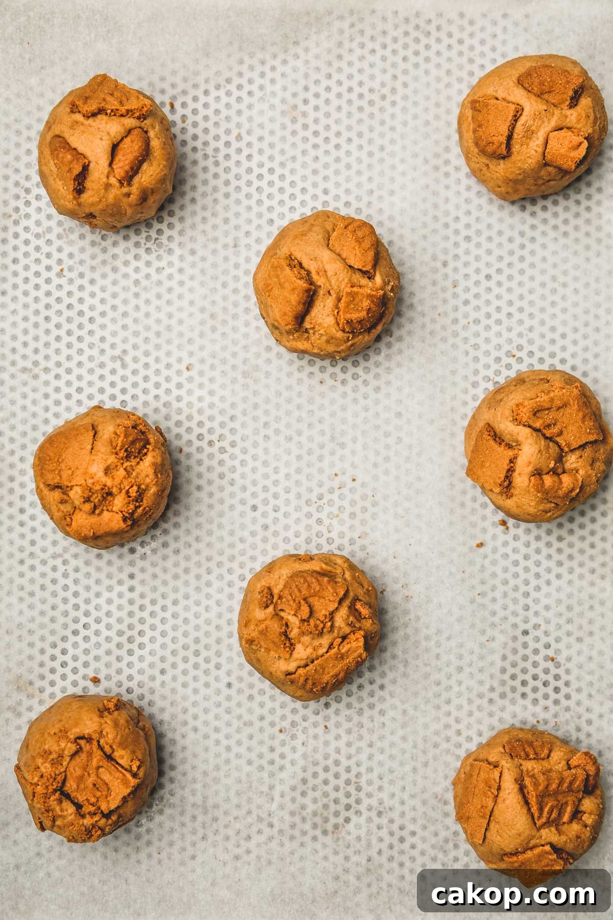 Biscoff Cookie Butter Cookies Recipe — Crunchy Spiced Biscuits 8 shaped biscoff cookie dough balls on a baking sheet
