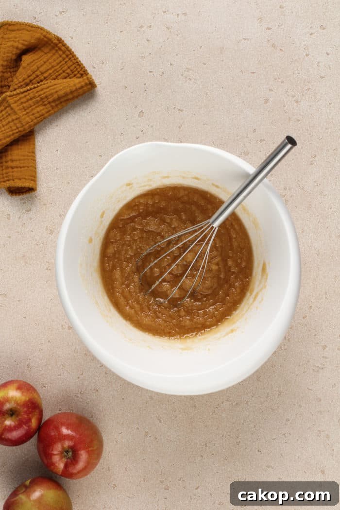 Vegetable oil and sugar whisked together in a white mixing bowl.