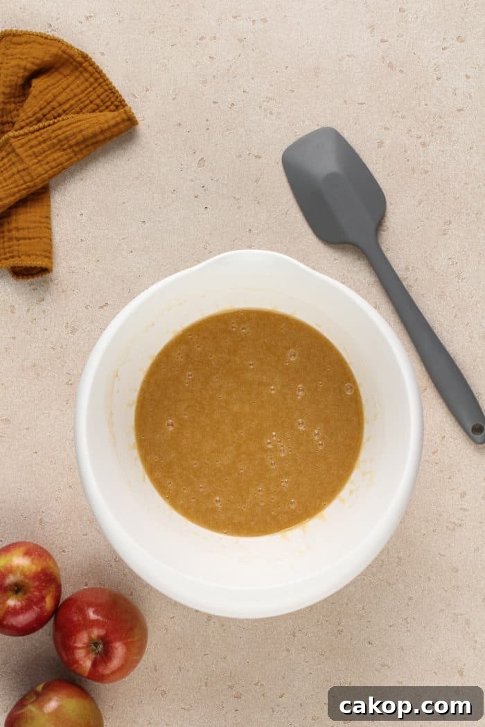 Wet ingredients for apple butter cake in a white mixing bowl.
