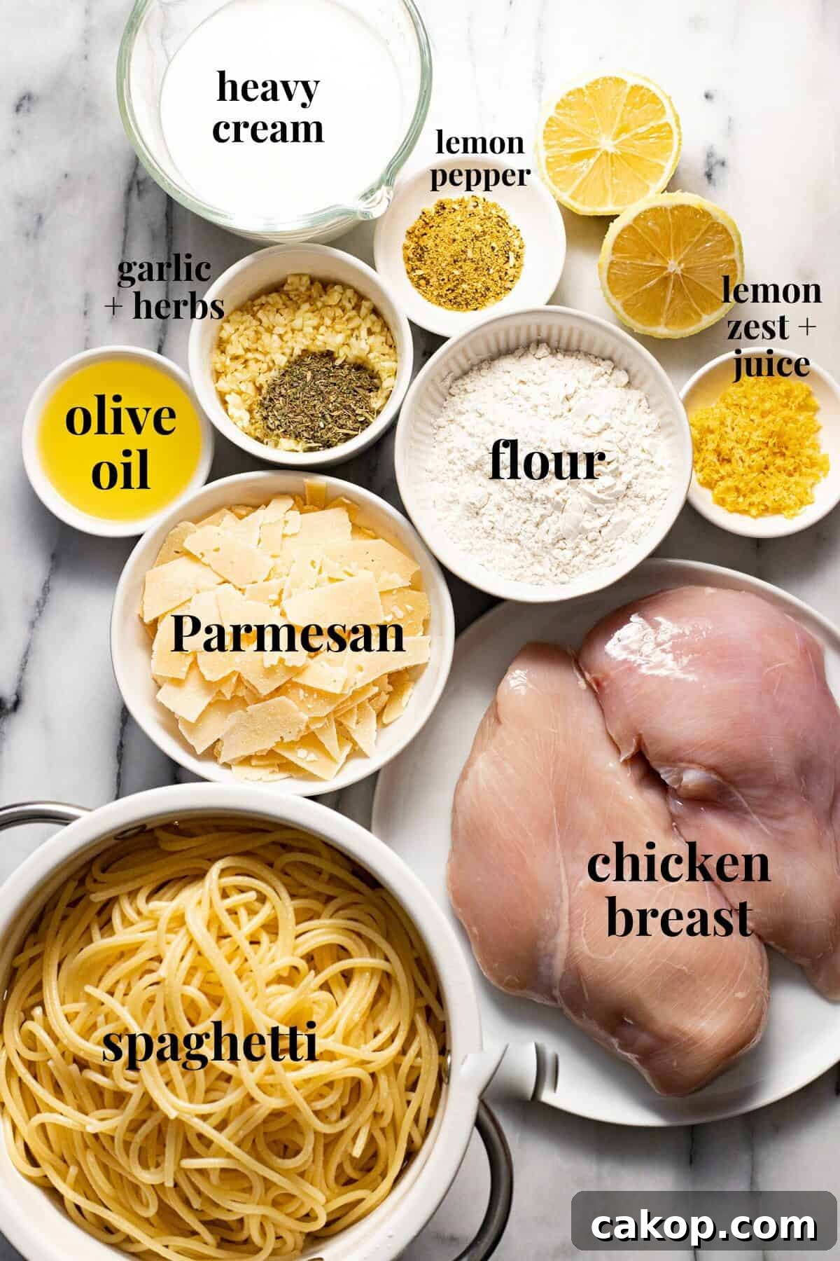 White marble counter top with bowls of ingredients to make creamy lemon chicken pasta.