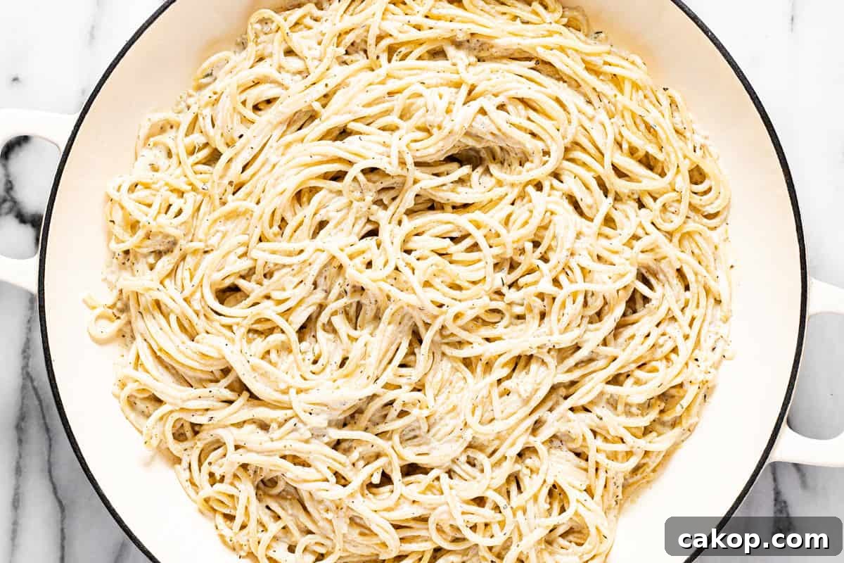 Large white pan filled with spaghetti tossed in a lemon cream sauce.