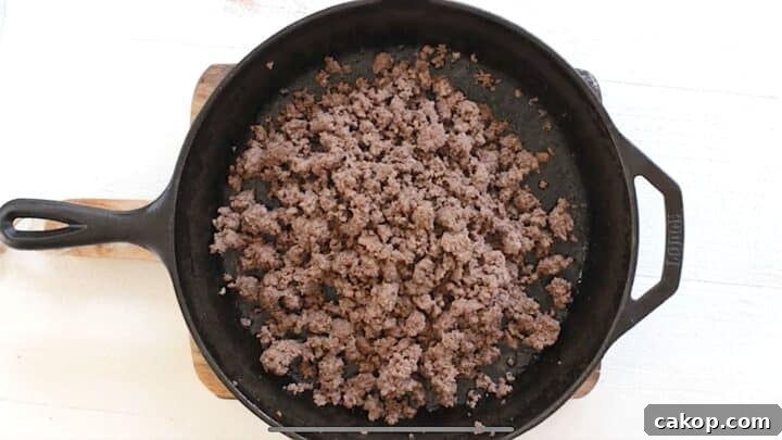 Browned ground beef drained of fat in a cast iron skillet.