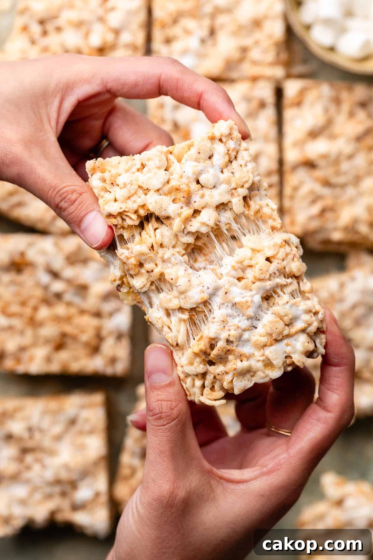 hands holding a golden graham rice krispies and pulling it apart