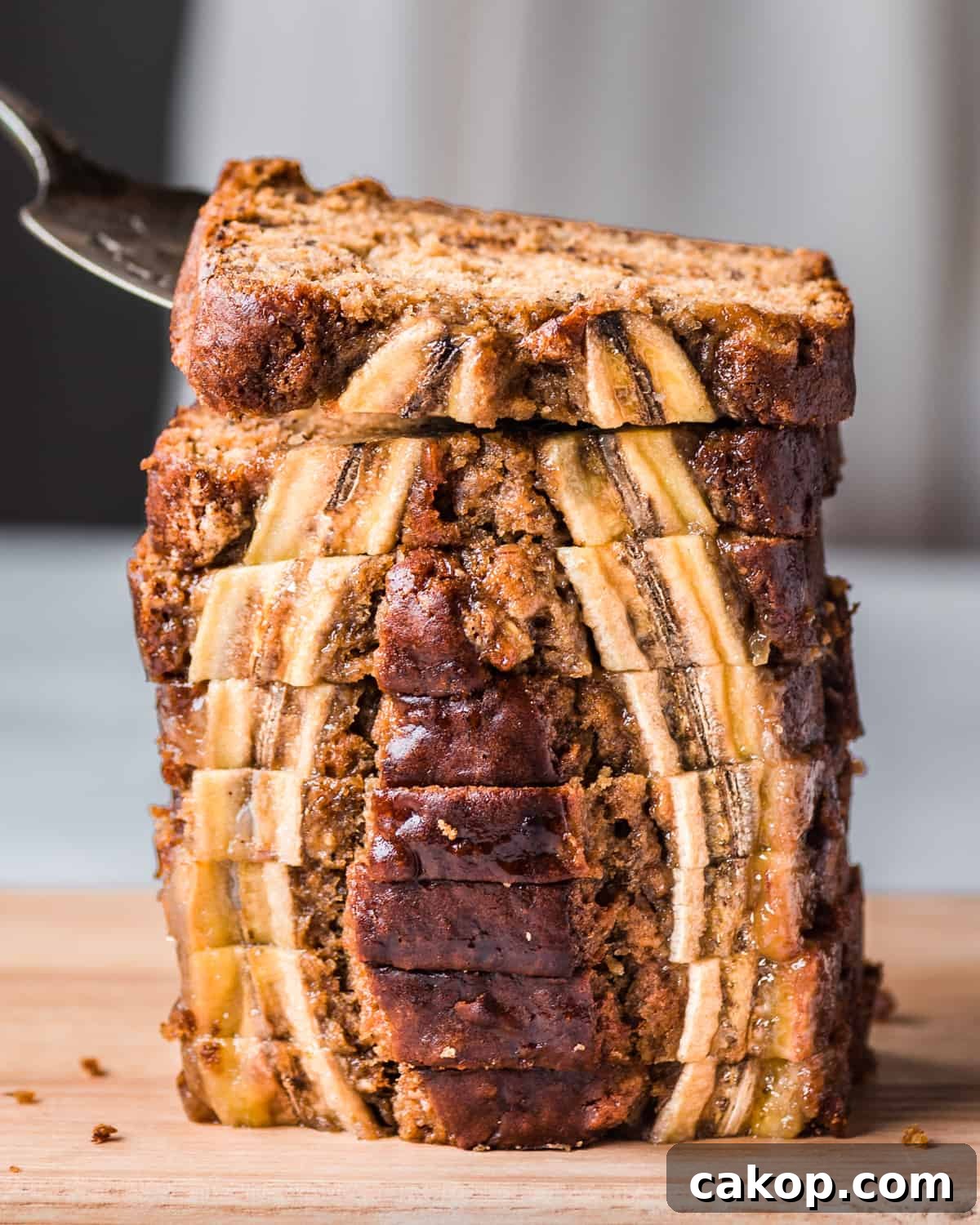 cake server lifting a slice of vegan banana bread from a tall stack of beautiful slices.