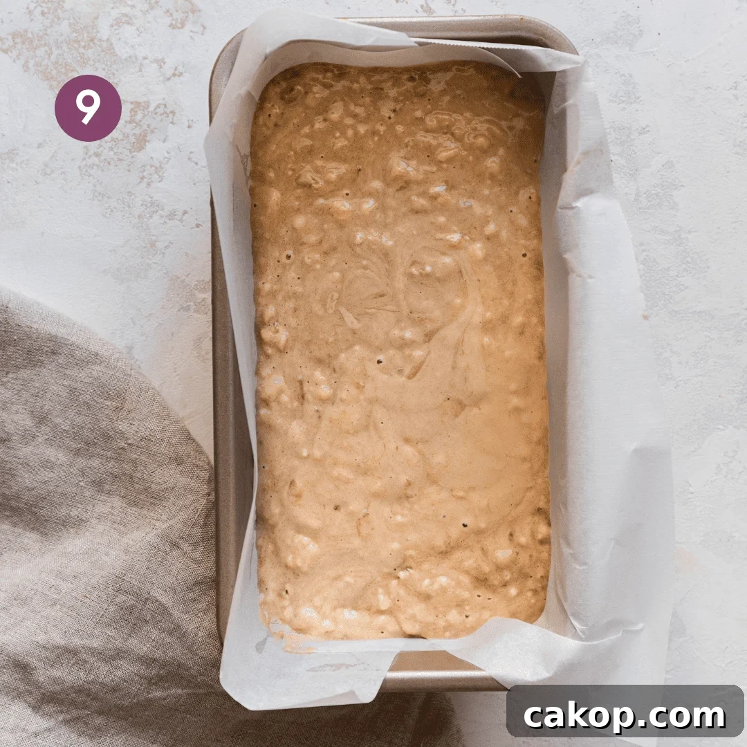 vegan banana bread batter poured into a parchment paper lined loaf pan.