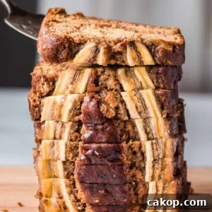 cake server lifting a slice of vegan banana bread from a tall stack of beautiful slices.