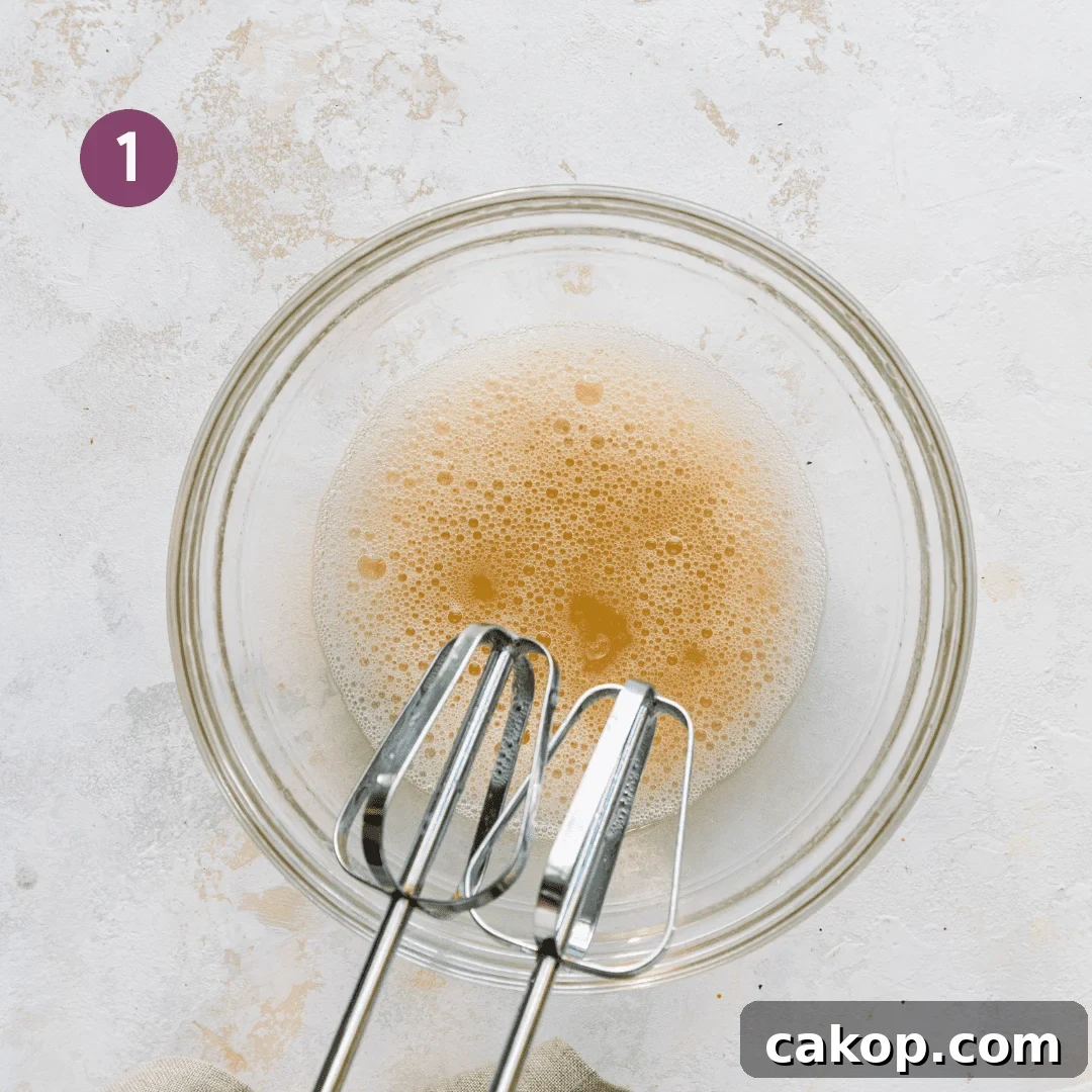 electric mixer whipping aquafaba in a glass bowl.
