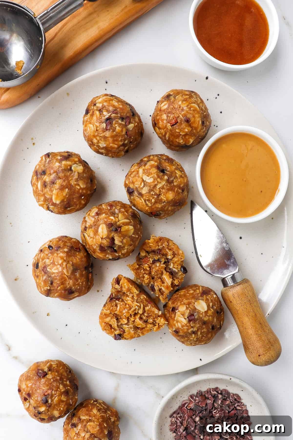 Bliss balls on a plate with a knife and dish of peanut butter.
