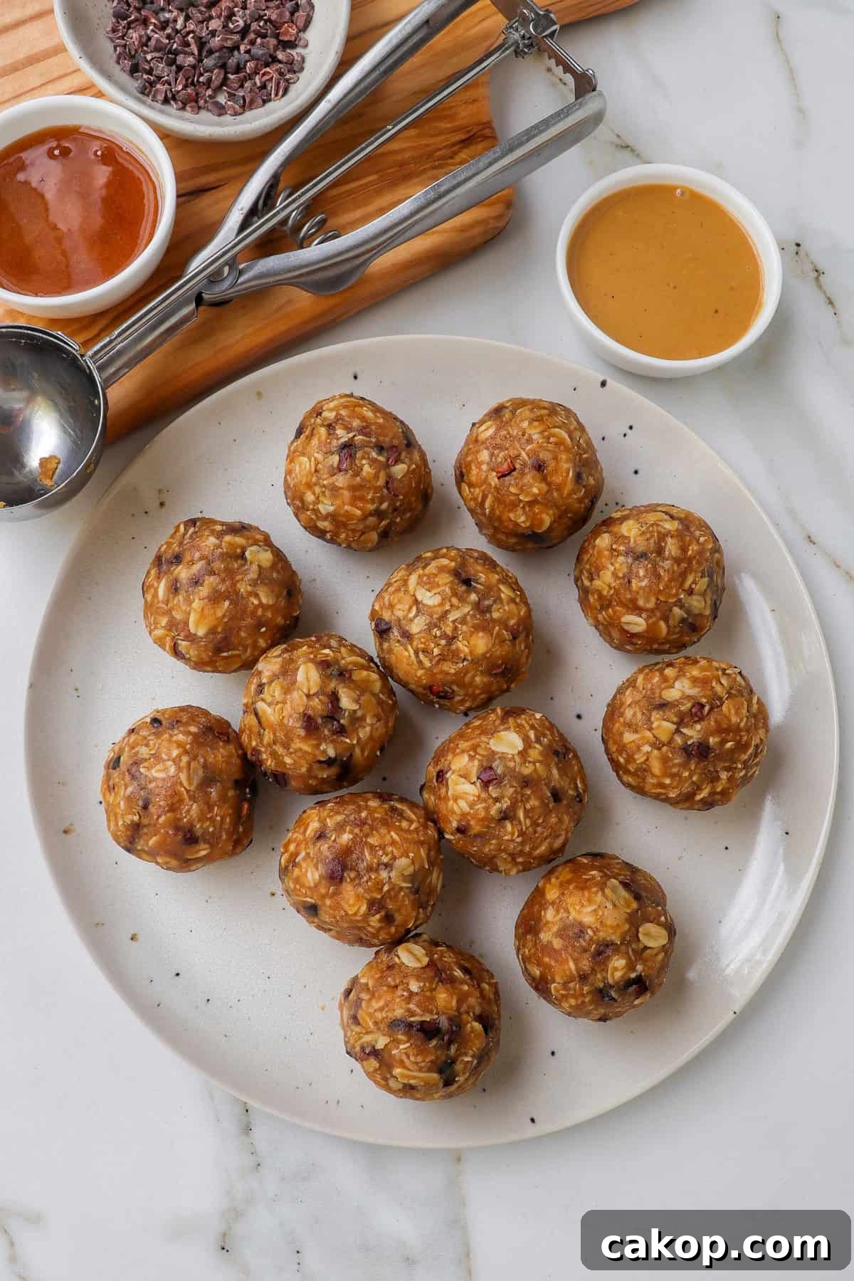 Bliss balls on a plate with peanut butter and ingredients on the side.