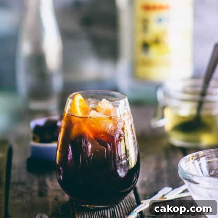 Greek ouzo cocktail with coffee liqueur and orange served over ice in a rounded glass.