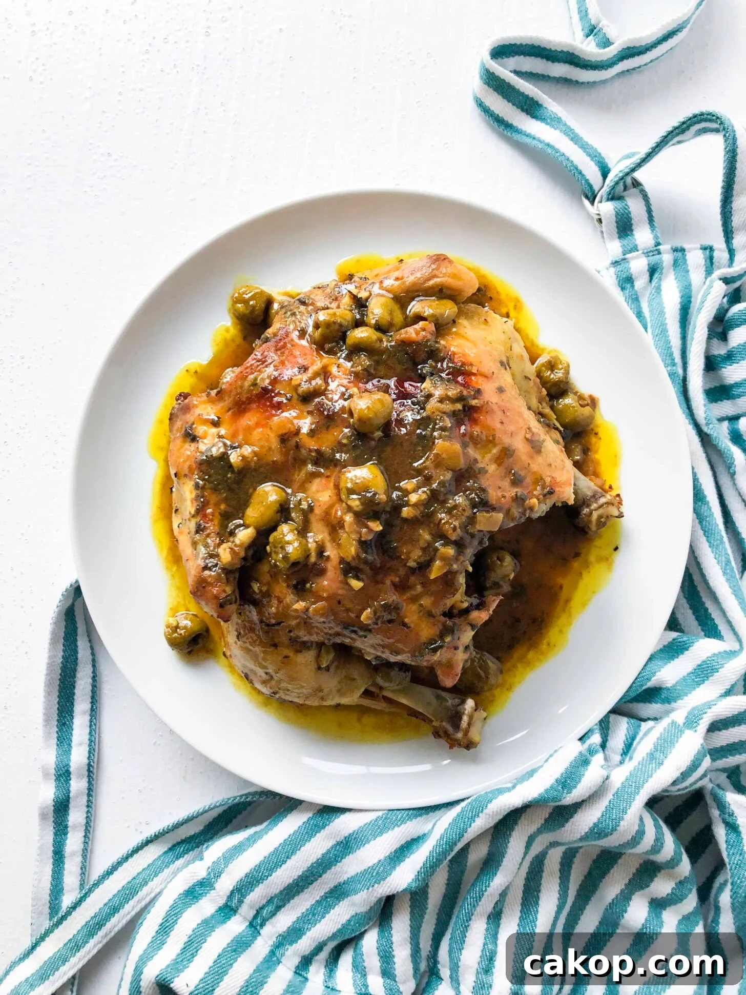 Moroccan chicken with olives on a plate with a striped towel