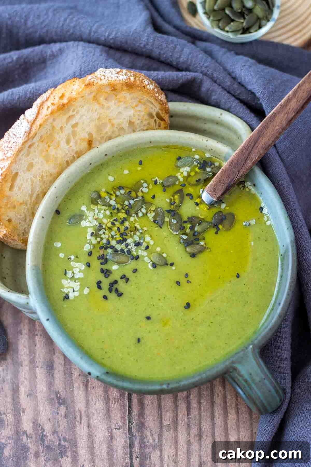 Fiery Roasted Broccoli Soup with Garlic and Chili Oil 6 Creamy broccoli soup served in a bowl with a slice of bread, topped with pumpkin seeds.