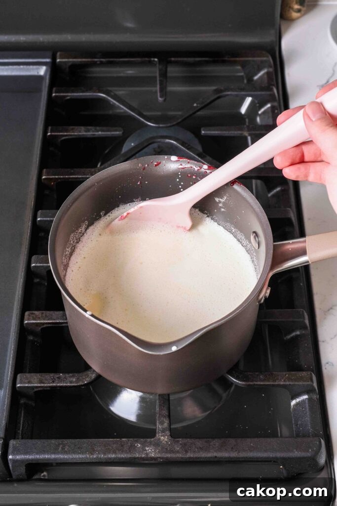 Homemade Strawberry Ice Cream Recipe with Fresh Berries 6 A spatula stirs custard in a medium pot over the stove.