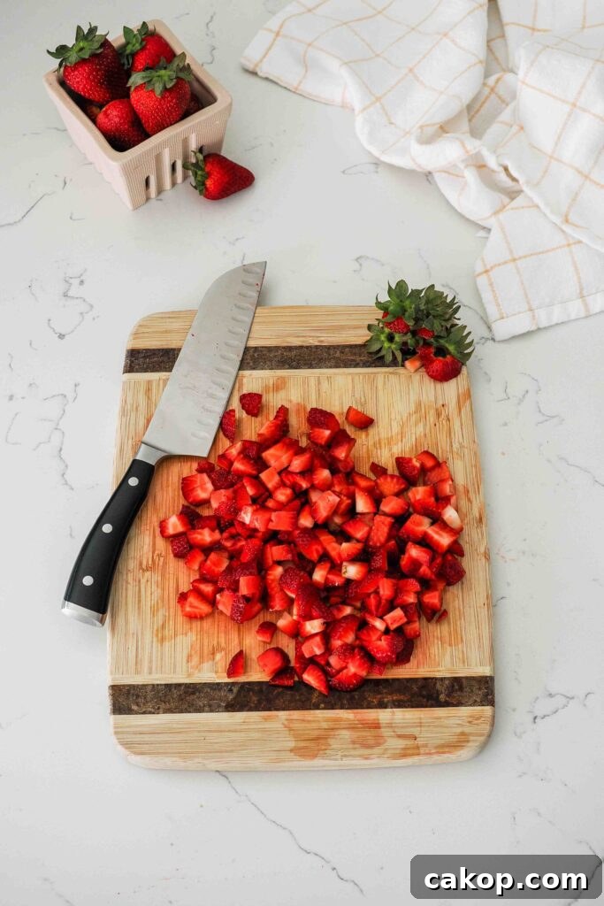 Homemade Strawberry Ice Cream Recipe with Fresh Berries 5 Diced strawberries on a wooden cutting board.
