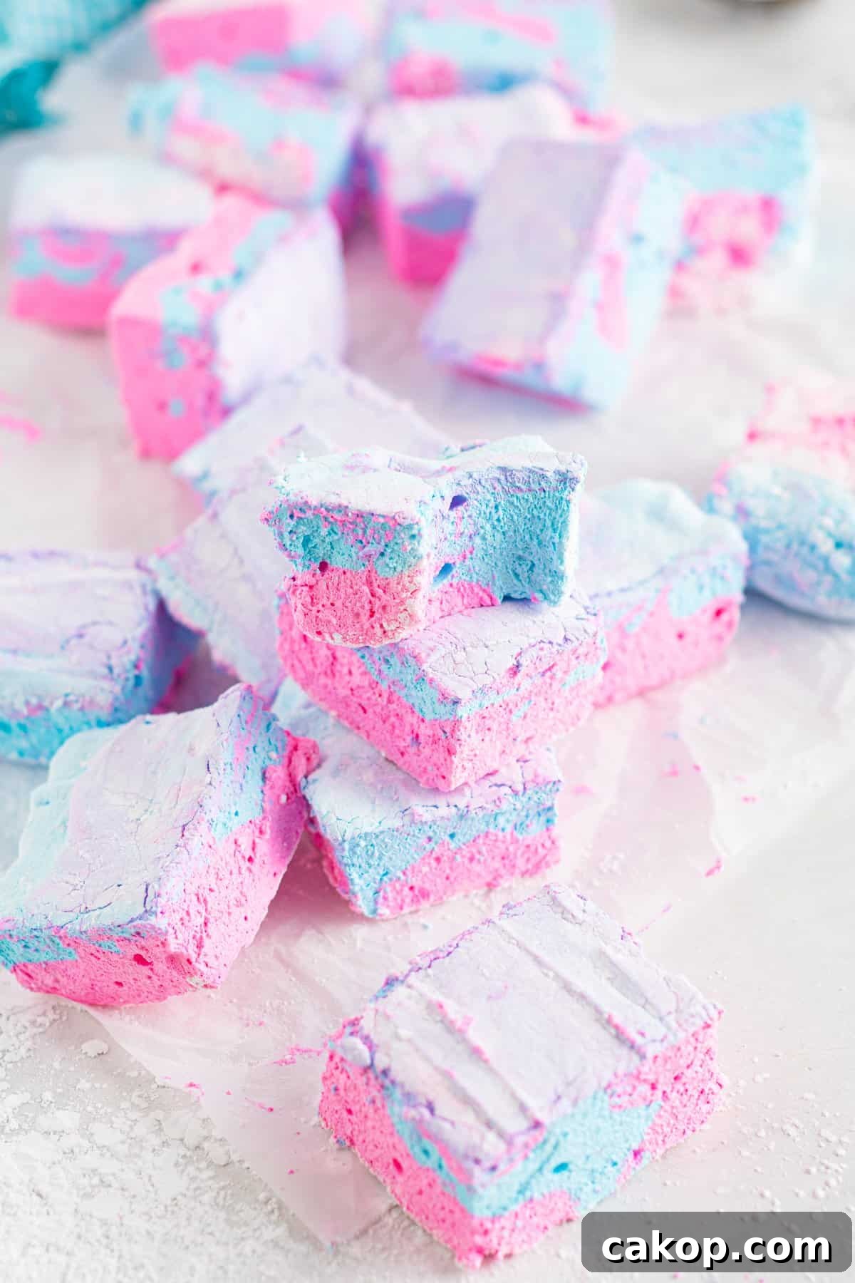 Cotton Candy Marshmallows: Fluffy Homemade Treats to Try 3 pile of cotton candy marshmallows with a partially eaten marshmallow on top.