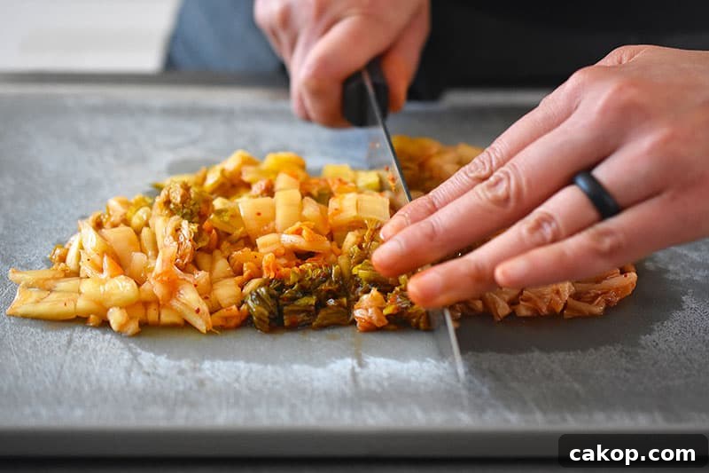 Kimchi Cauliflower Fried Rice — Whole30 & Gluten-Free Recipe 3 Someone chopping kimchi on a cutting board.
