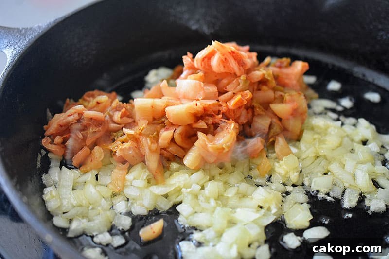 Kimchi Cauliflower Fried Rice — Whole30 & Gluten-Free Recipe 6 Kimchi on fried onions in a pan.
