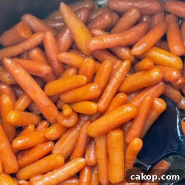 Close-up view of shiny glazed baby carrots cooking in a pan