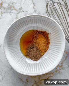 ingredients for cinnamon almonds added to white bowl against white surface