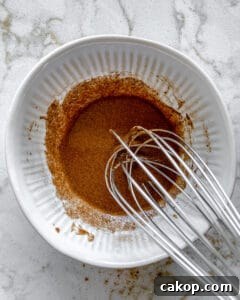 process of mixing spices for cinnamon almonds in white bowl with mixer