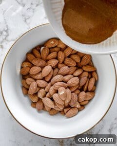 process showing spices being added to almonds in white bowl
