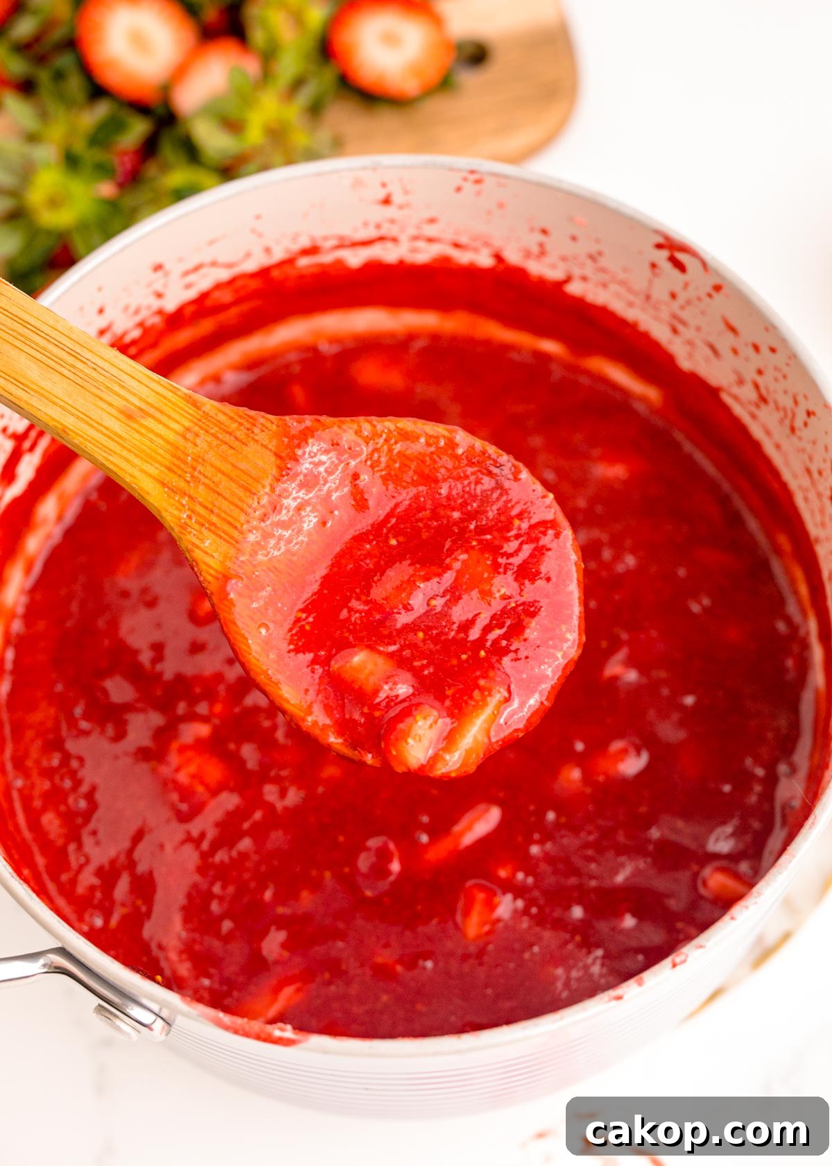 Strawberry Puree Recipe: Quick Homemade Strawberry Sauce 5 A wooden spoon scooping strawberry puree out of a pot.
