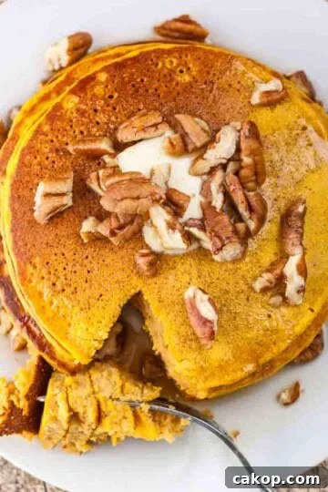 A stack of pumpkin pancakes topped with chopped pecans.