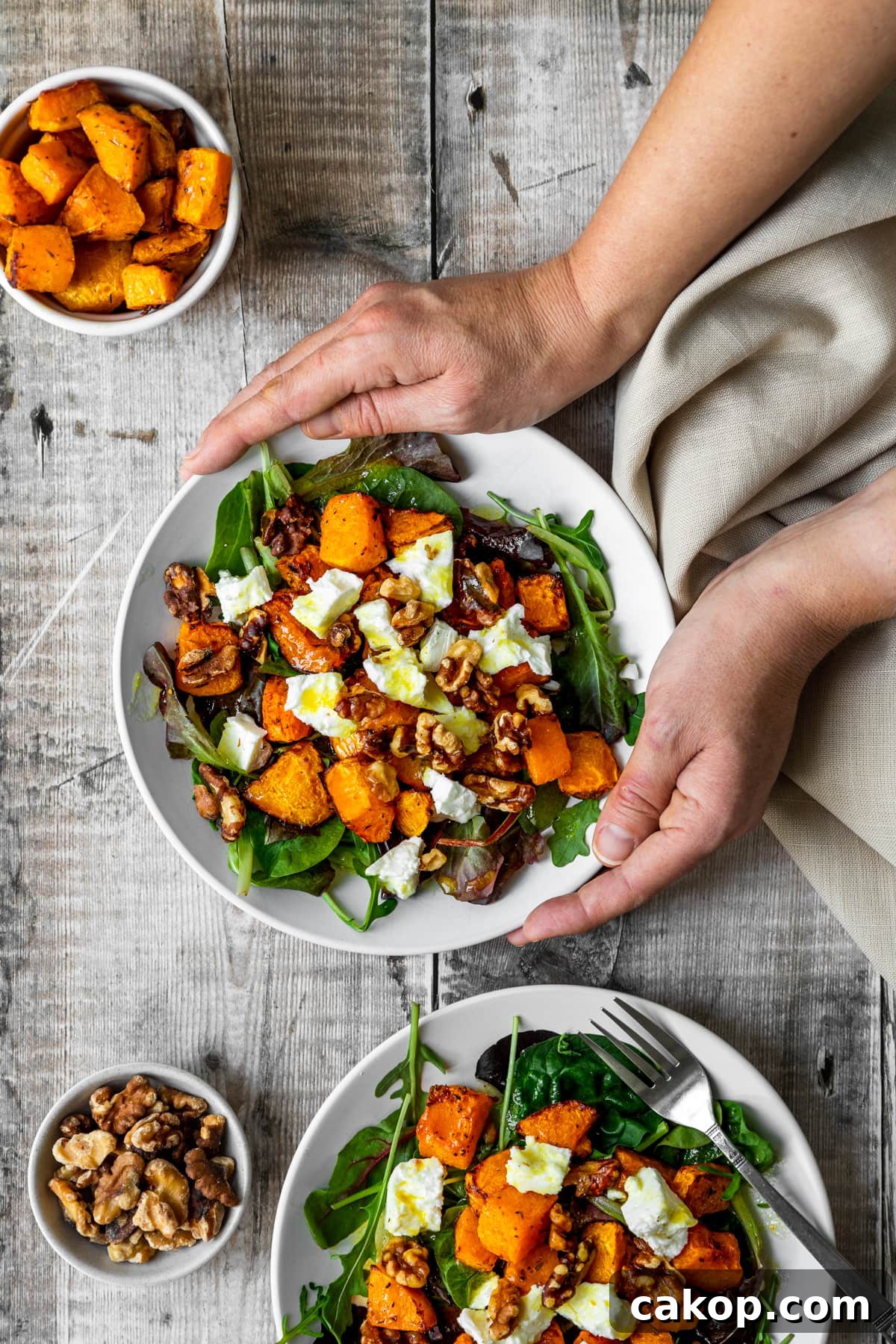 hands holding roasted butternut squash feta salad