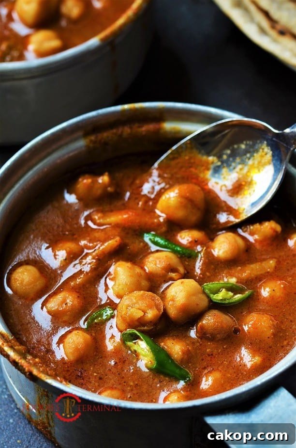 Instant Pot chana masala in a red sauce with a spoon