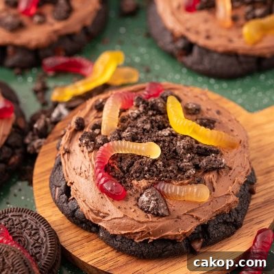 Big dirt cake cookies on a wooden board on a green surface.