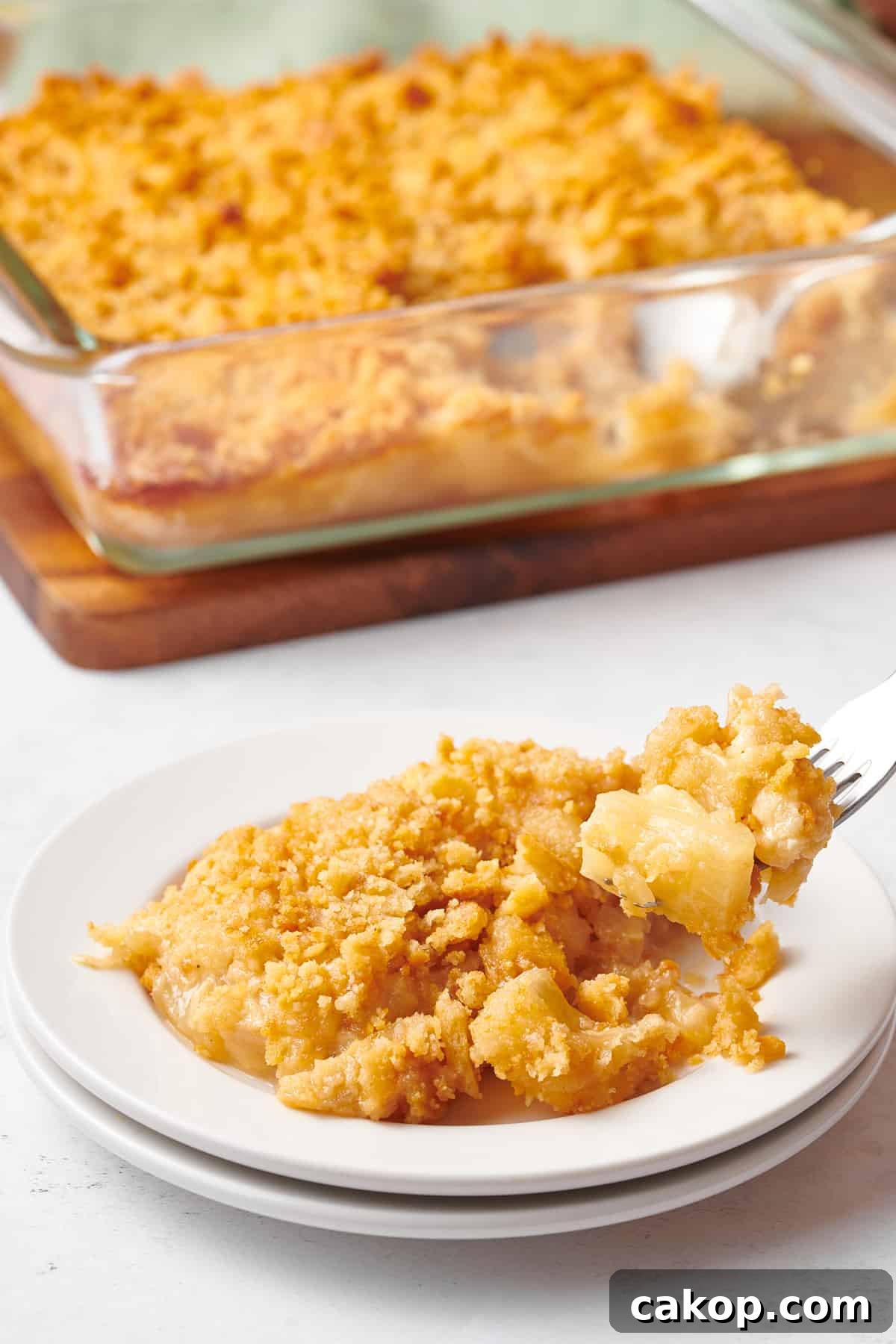 A plate of pineapple casserole with a fork holding a bite.